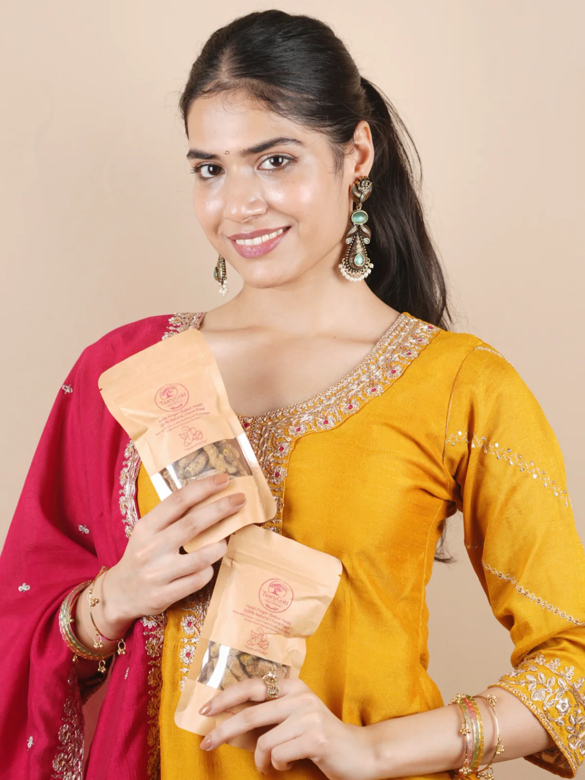 Smiling woman holding two packs of Taaru Gold Turmeric Fingers
